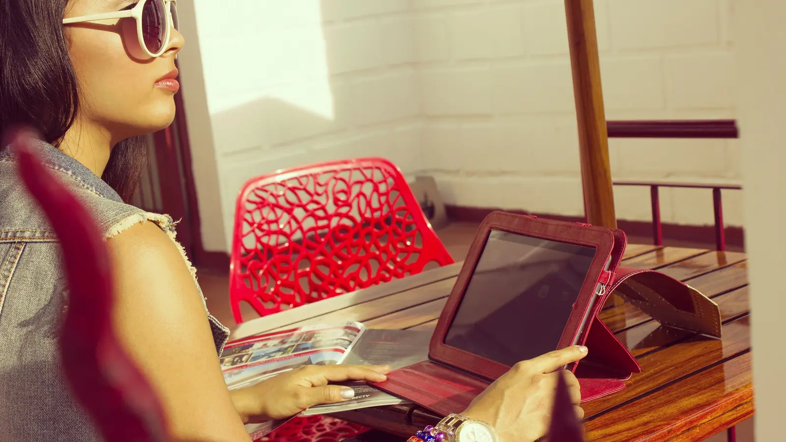 Frau auf einer Terrasse liest etwas auf einem Tablet