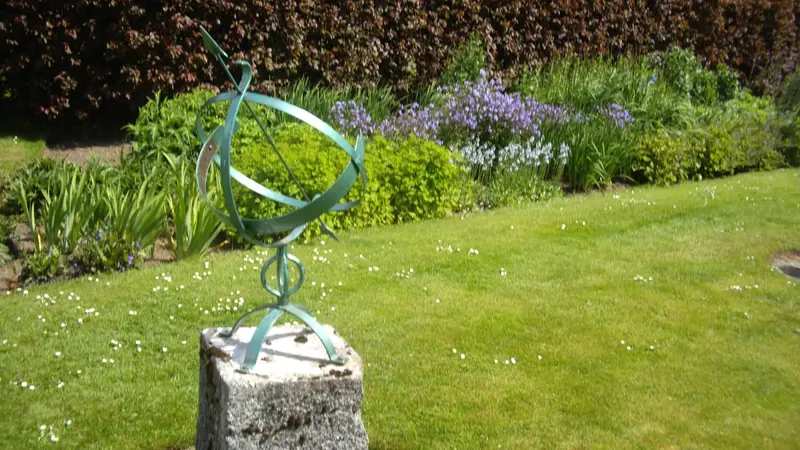 Sonnenuhr auf einem Rasen in einem Garten