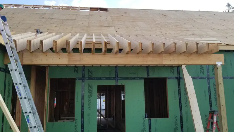 Ein Vordach aus Holz wird an einer Hauswand gebaut, Sparren liegen auf einem Träger